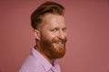 Adult handsome stylish redhead bearded smiling man in pink shirt