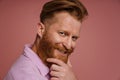 Adult handsome stylish redhead bearded smiling man touching his chin