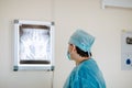 Adult white doctor posing near the x-rayed at the white operation room. Copy space