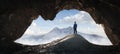 Adult Hiker Male standing inside a rocky mountain cave overlooking the nature scene