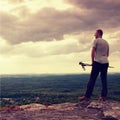 Adult hiker with poles in hand. Hiker take a rest on rocky view point above valley. Sunny day rocky mountains. Royalty Free Stock Photo