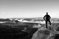 Adult hiker stand on cliff of sandstone empires park and watching over the misty and foggy morning valley Royalty Free Stock Photo