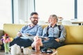 An adult hipster son and senior father sitting on sofa indoors at home, talking. Royalty Free Stock Photo