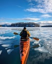 an adult on a kayak paddles along a frozen lake