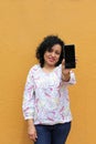 Adult latin brunette woman with curly hair uses her cell phone to send and receive messages, buy online and get discounts excited Royalty Free Stock Photo