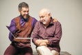 Adult learning and education. Happy young man with senior dad have fun watching funny video on laptop, smiling elderly Royalty Free Stock Photo