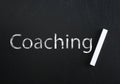 Adult learning. Piece of white chalk and word Coaching on black chalkboard Royalty Free Stock Photo