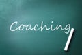 Adult learning. Piece of white chalk and word Coaching on green chalkboard Royalty Free Stock Photo