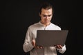 Adult long-haired man in glasses and shirt holding laptop