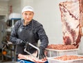 Adult male butcher sawing beef ribs