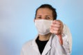 An adult male dressed in a white lab coat with a protective face mask on while giving a thumbs down. Ready to work in a clean room