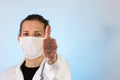 An adult male dressed in a white lab coat with a protective face mask on while giving a thumbs up. Ready to work in a clean room