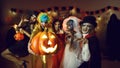 Group of adult friends with a jack-o-lantern having fun at a costume party at home