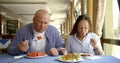 Adult male and female are having breakfast in canteen of hotel in sunny morning