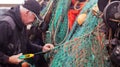 Adult male fisherman standing on a dock, reaching out to grab a set of fishing nets