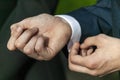 Adult male in a formal wear fashion suit adjusting and fastening his shirt sleeve button