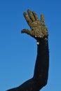 Adult male hand covered with black healing mud and another layer of sand with small stones, raised agains the blue summer skies. Royalty Free Stock Photo