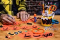 An adult male making making construction paper jack-o-lanterns, focus is on the Marker Tip. Many crafts are on the table with