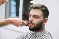 Adult male model with beard trimming at barber shop. Close up portrait of a client doing hairstyle in light barbershop. Male Royalty Free Stock Photo