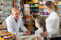 Adult male pharmacist helping customers