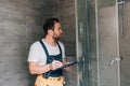 Adult male plumber making notes in clipboard while checking shower