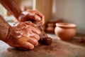 Adult male potter master modeling the clay plate on potter`s wheel. Top view, closeup, hands only. Royalty Free Stock Photo