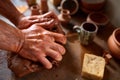 Adult male potter master modeling the clay plate on potter`s wheel. Top view, closeup, hands only. Royalty Free Stock Photo