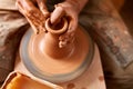 Adult male potter master modeling the clay plate on potter`s wheel. Top view, closeup, hands only. Royalty Free Stock Photo