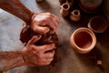 Adult male potter master modeling the clay plate on potter`s wheel. Top view, closeup, hands only. Royalty Free Stock Photo