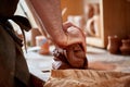 Adult male potter master modeling the clay plate on potter`s wheel. Top view, closeup, hands only. Royalty Free Stock Photo