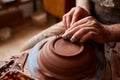 Adult male potter master modeling the clay plate on potter`s wheel. Top view, closeup, hands only. Royalty Free Stock Photo