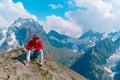 Adult male in red hoodie with hood enjoying beautiful view in mountainous area.