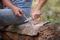 adult male removing bark from branch with sharp knife