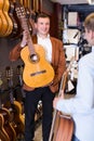 Adult male seller showing guitar to boy client