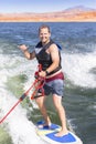 Adult male smiling and enjoying a day on the lake while he attempts to wake surf behind a motor boat.
