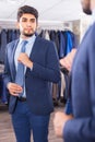 Adult male is trying on tie in front of the mirror