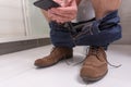 Adult male wearing jeans and shoes using phone while sitting on Royalty Free Stock Photo