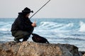 Adult man adjusting his fishing gear on a rocky shore of Haifa, Israel