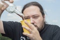 An adult man with a beard is trying to pour wine from a nearly empty bottle