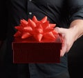 Adult man in a black shirt holds a red square box with a knotted bow Royalty Free Stock Photo