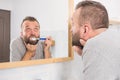 Bored guy brushing his teeth in bathroom