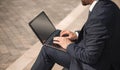 Adult man in business suit sits with laptop on the street. Side view of Caucasian man working on the steps. High quality Royalty Free Stock Photo