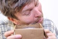 An adult man cautiously looks into an open cardboard box