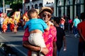 Adult man in dark glasses carries little son walking by city street at dominican carnival