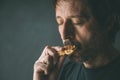 Adult man eating homemade cookie while standing by the window in morning