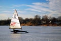 An adult man glides across a frozen river on his ice yacht