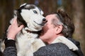 Adult man in gray sweatshirt hugs beloved Siberian Husky dog, true love of human and pet