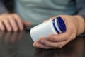 An adult man holds a white vial in his hands