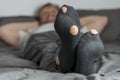 Adult man with a hole in his socks lying in bed, closeup. Man with worn out socks relaxing