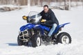 An adult man in jacket riding snowmobile in the winter forest